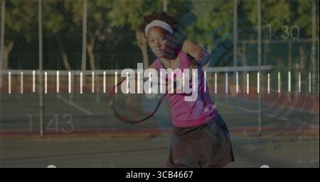 Schwungvolle Sportfrau in Sportbekleidung auf dem Tennisplatz, mit Schläger, Ball, Kettenzaun Stockfoto