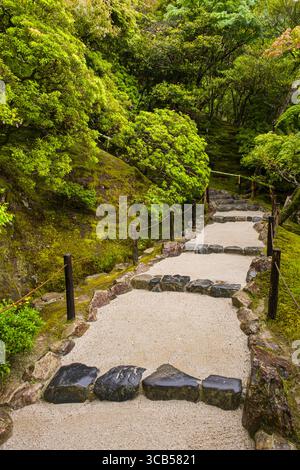 Ein ruhiger Steinweg schlängelt sich durch einen lebendigen japanischen Garten, umgeben von sattem Grün im Higashiyama Jisho-Ji buddhistischen Tempel in Kyoto Stockfoto