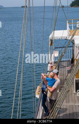 Die Familie mit einem Kind genießt an einem sonnigen Tag eine malerische Bootsfahrt und beobachtet das weite, ruhige Wasser. Die Atmosphäre ist fröhlich und entspannend, perfekt für ein Mem Stockfoto