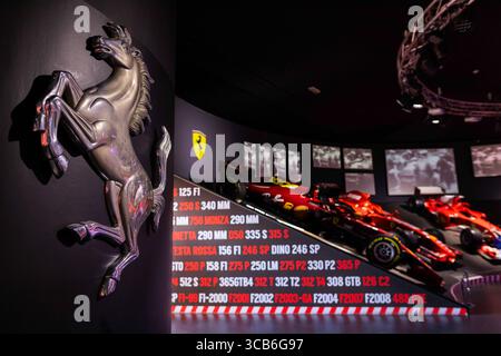 Ferrari Formel-1-Museum mit roten Rennwagen, Chrom-Emblem und historischen F1-Grafiken, die die italienische Renngeschichte zelebrieren Stockfoto