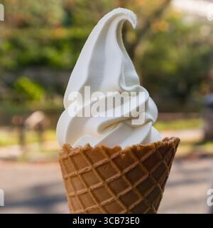 Köstliches Eis mit Vanillegeschmack, serviert in einem knusprigen Waffelkegel, im Freien in einer sonnigen Umgebung, die die Freude am Frozen weckt Stockfoto