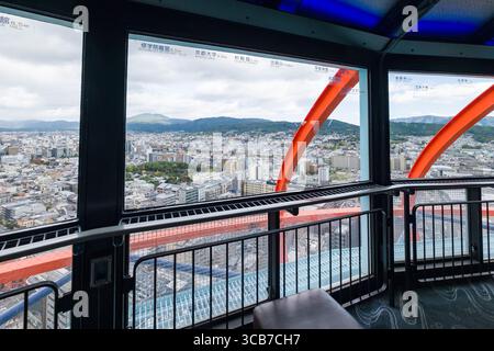 Ein erhöhter Blick auf Kyoto's städtische Architektur und die umliegenden Berge, von der Aussichtsplattform des Nidec Kyoto Tower durch große Fenster aufgenommen. Higa Stockfoto
