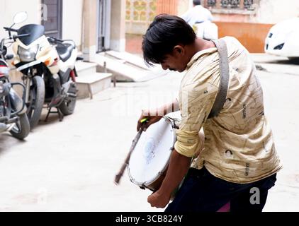 Delhi, Indien, 21. Juni 2024: Ein Mann, der während einer Straßenfeier mit Begeisterung eine traditionelle Trommel spielt und den Rhythmus und die Energie der Kultur zeigt Stockfoto