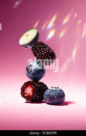 Nahaufnahme von saftiger Brombeere und Blaubeere mit Wassertropfen auf rosa Hintergrund, Makrofoto von brombeere mit Wassertropfen auf rosa Hintergrund. Stockfoto