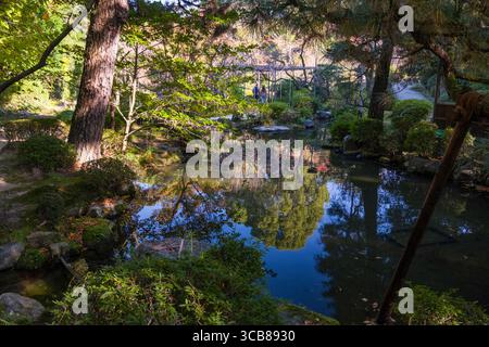 Heian Shrine Garden mit einem kleinen Teich, umgeben von üppigem Grün und Bäumen, mit klaren Reflexen des Laubs auf dem Wasser, schaffen einen Frieden Stockfoto