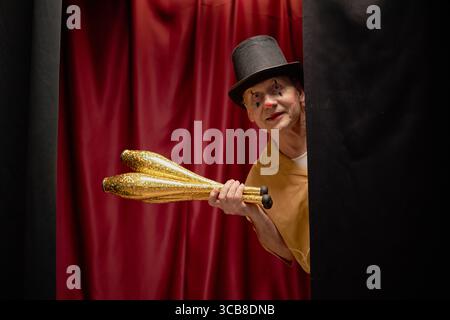 Ein alter Mann, der als Clown gekleidet ist und Jonglierclubs hält Stockfoto