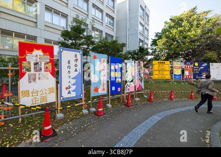 Farbenfrohe dekorative Banner, die im Freien während eines städtischen Kulturfestivals mit vorbeiziehenden Besuchern an der Universität Kyoto gezeigt werden Stockfoto