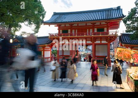 Eine geschäftige Szene in der Nähe des Yasaka Jinja Nishiromon Gate, in der Besucher Imbissstände und lokale Traditionen in einem friedlichen und kulturellen Ambiente genießen können Stockfoto