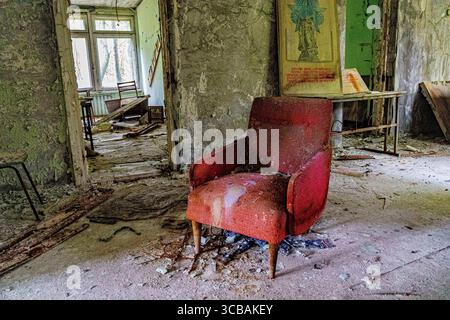 5. Mai 2023, Pripyat, Kiew Oblast, Ukraine: Ein einziger roter Stuhl sitzt zwischen dem Trümmer eines zerbröckelten Hauses in Pripyat. (Foto: © Gabriel Romero/ZUMA Press Wire) Stockfoto