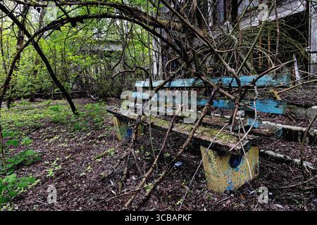 5. Mai 2023, Pripyat, Kiew Oblast, Ukraine: Eine Parkbank vor einem verfallenen Wohnkomplex in Pripyat. (Foto: © Gabriel Romero/ZUMA Press Wire) Stockfoto
