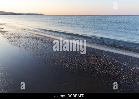Küstenlandschaft des Kaspischen Meeres, Buzowna, Aserbaidschan. Eine idyllische Küste mit Muscheln, die auf dem nassen Sand verstreut sind Stockfoto