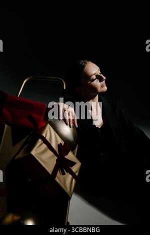 Frau in Schwarz mit Weihnachtsgeschenken in Schubkarre Stockfoto