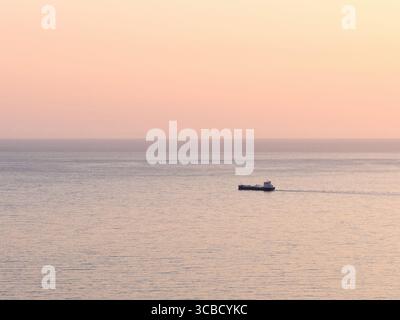 Frachtschiff segelt auf ruhigem Ozean bei Sonnenuntergang in reykjavik, island Stockfoto