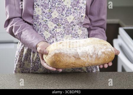 Eine Frau mit einer Schürze und einem Brotlaib Stockfoto