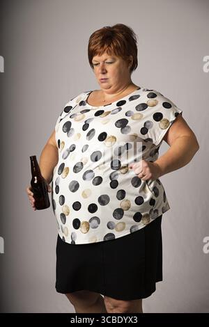 Fünfzig Frauen, die auf eine braune Bierflasche herabschauen Stockfoto