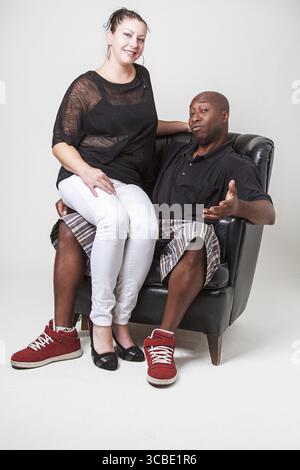 Kaukasische Frau sitzt auf einem schwarzen Mannschoß Stockfoto