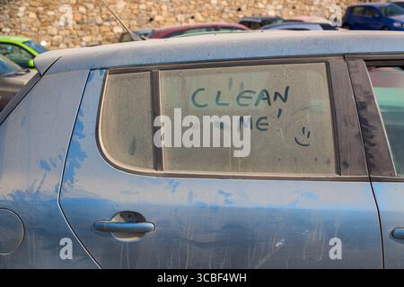 Die Inschrift reinigt mich auf einem schmutzigen Auto mit einem Lächeln. Stockfoto