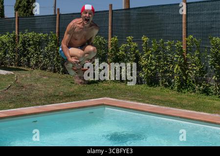 Ein Mann taucht in ein Schwimmbad mit einer rot-weißen Badekappe Stockfoto