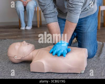 Nahaufnahme der Hände. Männlicher Student, der während eines ersten-Hilfe-Trainings die richtige Thoraxkompressionstechnik an einer HLW-Übungspuppe (Basic Life Support, BLS) übt Stockfoto
