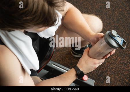 Porträt eines jungen Bodybuilders und sportlichen Mannes mit Proteinshake beim Training im Fitnessstudio oder Fitnesscenter. Blick von oben. Nahaufnahme. Stockfoto
