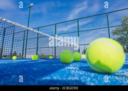 Ein flacher Blick auf einen Padelplatz mit Bällen und Netz bei einem sonnigen Sommersportkonzept Stockfoto