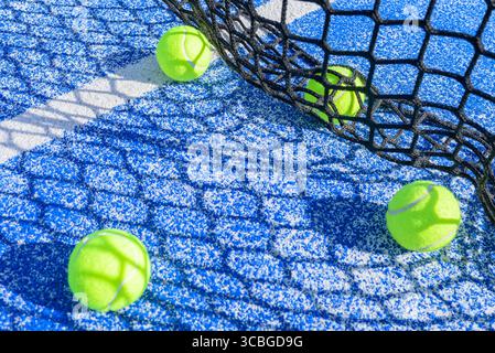 Padelbällchen und der Schatten des Netzes auf einem blauen Platz an einem sonnigen Sommererholungskonzept Stockfoto