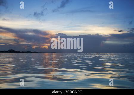 Die letzten Sonnenstrahlen, die durch dunkle Wolken ragen Stockfoto