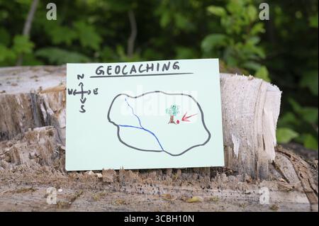 Geocaching, Freizeitaktivitäten im Freien, Navigation zum Verstecken und Suchen von Containern, Geocache-Standort im Wald, Schatzjagd-Spiel, Hinweis auf Baum tr Stockfoto