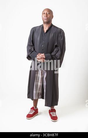 Ein kahler schwarzer Mann trägt eine Prediger-Toga, kurz und Sneaker Stockfoto