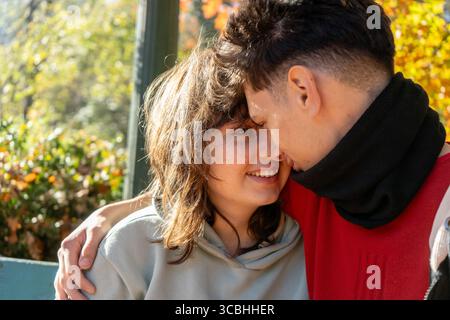 Romantisches Paar, das einen zärtlichen Moment gemeinsam in einem lebhaften Herbstpark genießt Stockfoto