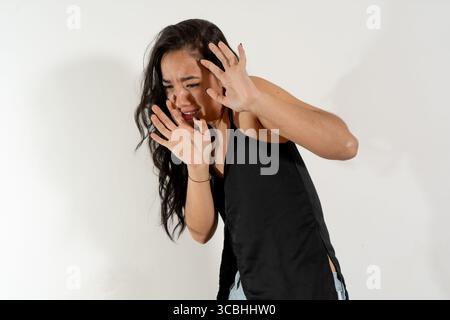 Studio-Aufnahme einer jungen Frau, die Angst und Angst zeigt und ihre Hände in einer defensiven Geste hebt Stockfoto