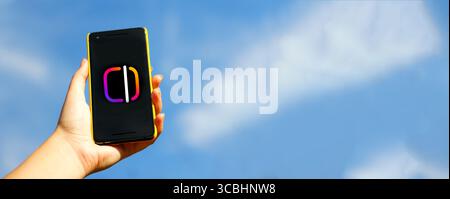 Ein minimalistisches Foto einer Videobearbeitungs-App, das auf einem Telefon geöffnet wird, mit einem leuchtend blauen Hintergrund. Auf dem Bildschirm wird ein modernes Logo für Rollen und Bearbeitungen angezeigt, mit Pl Stockfoto