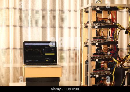 Eine selbstgemachte Krypto-Mining-Anlage, gebaut aus verschiedenen Computerkomponenten in einer provisorischen Farm. Die komplizierte Konstruktion steht vor einem einfachen Hintergrund Stockfoto