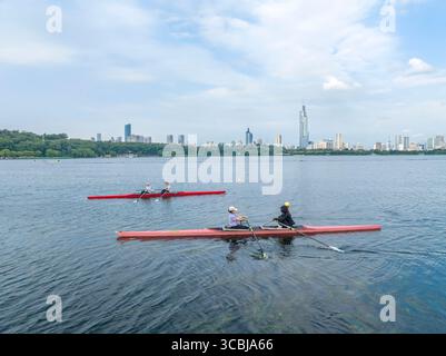 Peking, China. August 2025. Ein Drohnenfoto vom 8. August 2025 zeigt Menschen, die im Xuanwu Lake Park in Nanjing, der Provinz Jiangsu im Osten Chinas, Kanus paddeln. Da das Land diesen Freitag den nationalen Fitness-Tag begeht, ein Erbe der Olympischen Spiele 2008 in Peking, nehmen immer mehr Menschen einen aktiven Lebensstil auf. Quelle: Shi Jun/Xinhua/Alamy Live News Stockfoto