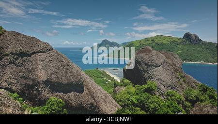 Atemberaubende Aussicht auf tropische Inseln aus dem türkisfarbenen Ozean, eingerahmt von majestätischen Felsen, die eine atemberaubende Landschaft auf Fidschi schaffen. Fantastischer Naturreisehintergrund. Drohnenflug Stockfoto