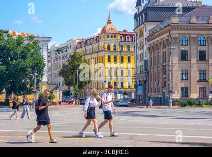 Junge Touristen spazieren durch das Viertel Podil in Kiew, Ukraine, mit Smartphones und genießen das Sommerwetter und die historische Archi Stockfoto