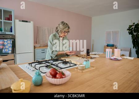Eine ältere Frau, die in einer modernen Küche Teig zubereitete Stockfoto