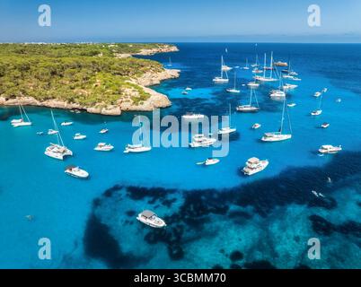 Blick aus der Vogelperspektive auf Luxusyachten und Boote, die im türkisfarbenen Meer vor Anker liegen Stockfoto