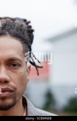 Afroamerikaner, der draußen im Hemd mit Kragen steht und die Haare zurückgebunden, Kopierraum. Porträt, männlich, natürliches Licht, Urban, kontemplativ Stockfoto