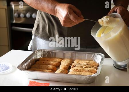 Frau, die Tiramisu-Dessert in der Küche zubereitet Stockfoto