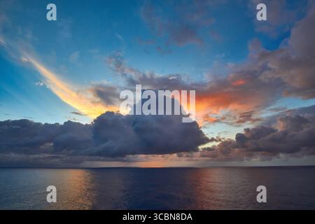 Lebendiger Sonnenuntergang über dem ruhigen Ozean mit farbenfrohen Wolken und ruhigem Himmel Stockfoto