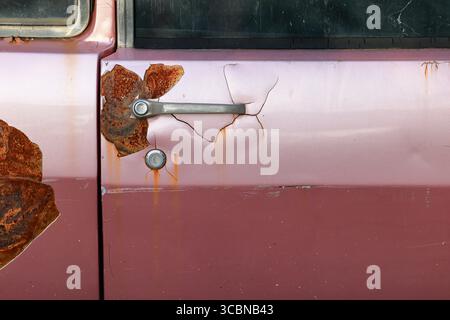 Der Türgriff eines verlassenen alten, rostigen Autos am Straßenrand. Stockfoto