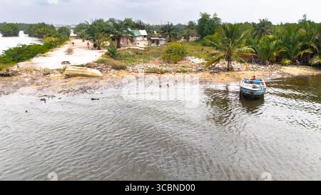 Aus der Vogelperspektive eines ruhigen Bootes, das sanft auf dem glitzernden Wasser in der Nähe des Ufers schwimmt, Borikiri, Port Harcourt, Nigeria. Stockfoto