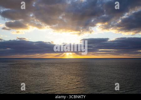 Die strahlenden Finger der Sonne erstrecken sich aus der Vogelperspektive über den riesigen Atlantik und malen den Himmel mit Gold- und Lavendeltönen, Miami Beach, Florida, USA. Stockfoto