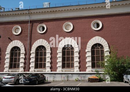 Moskau, Russland - 3. August 2025: Historisches Gebäude aus rotem Backstein mit Rundbogenfenstern, umrahmt von weißem Stein, fotografiert unter klarem blauem Himmel Stockfoto