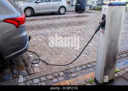 Das Elektroauto wird von der Ladestation auf der Straße aufgeladen. Ökologisch saubere Technologien für den Umweltschutz. Stockfoto