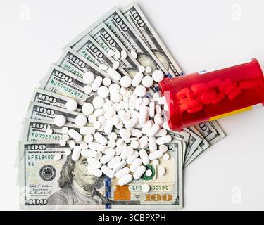 Verschreibungspflichtige Pille Flasche kippte mit Tabletten, die über gefächerte hundert Dollar Scheine auf weißem Hintergrund verschüttet wurden, symbolisieren steigende medizinische Kosten Stockfoto