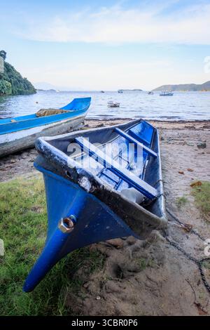 Lebhafte alte Holzfischboote ruhen am Sandstrand in Brasilien, mit hellen Farben, rustikalen Texturen und traditioneller Küstenkultur. Stockfoto