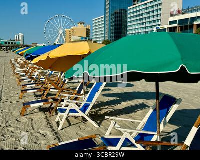 Liegen mit Sonnenschirmen, die strategisch am Myrtle Beach vor der Promenade angeordnet sind. Stockfoto