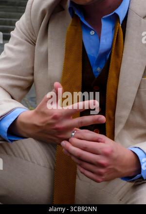 Ein Mann im Anzug hält die Hände hoch und zeigt einen Ring am Finger. Stockfoto